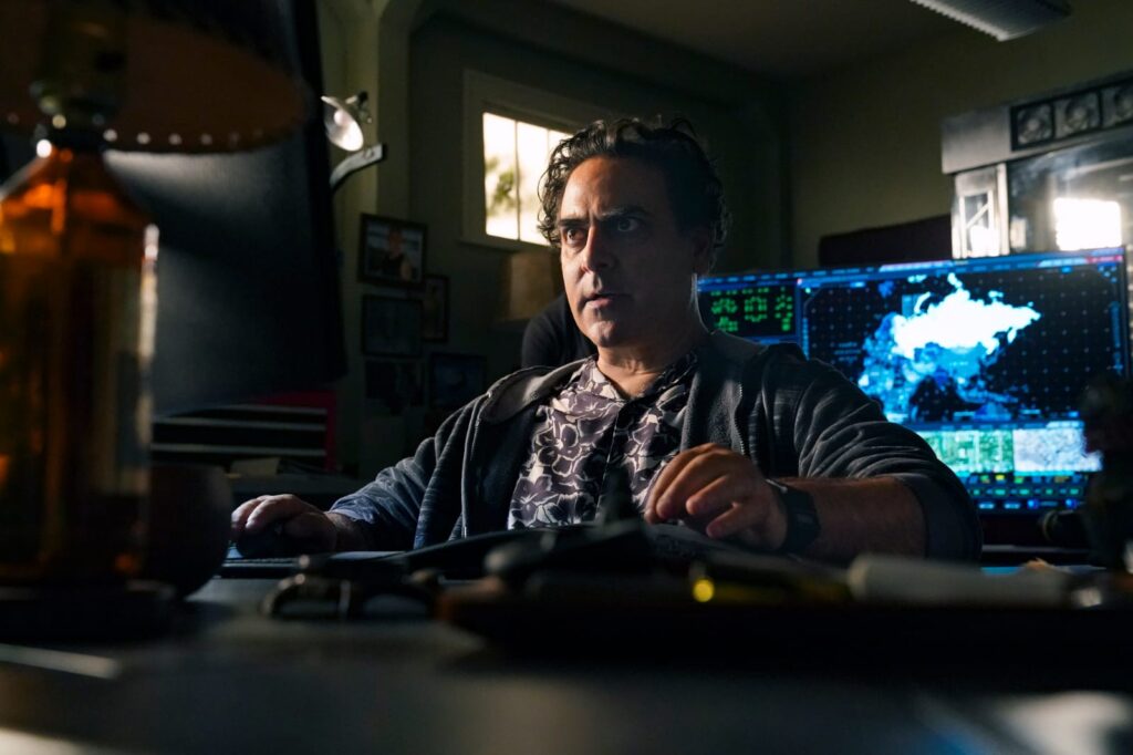 NCIS Star Reveals Franchise’s First Female-Led Show Set Is "Empty and full of weeds" 3 Jason Antoon working diligently on a computer in a still from NCIS: Hawai'i.