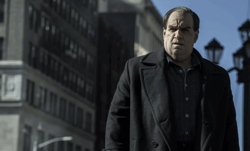 ‘The Penguin’ Season 2: Everything We Know So Far 1 Colin Farrell as Oz Cobb is looking at someone with his mouth slightly open. He is wearing a black coat.