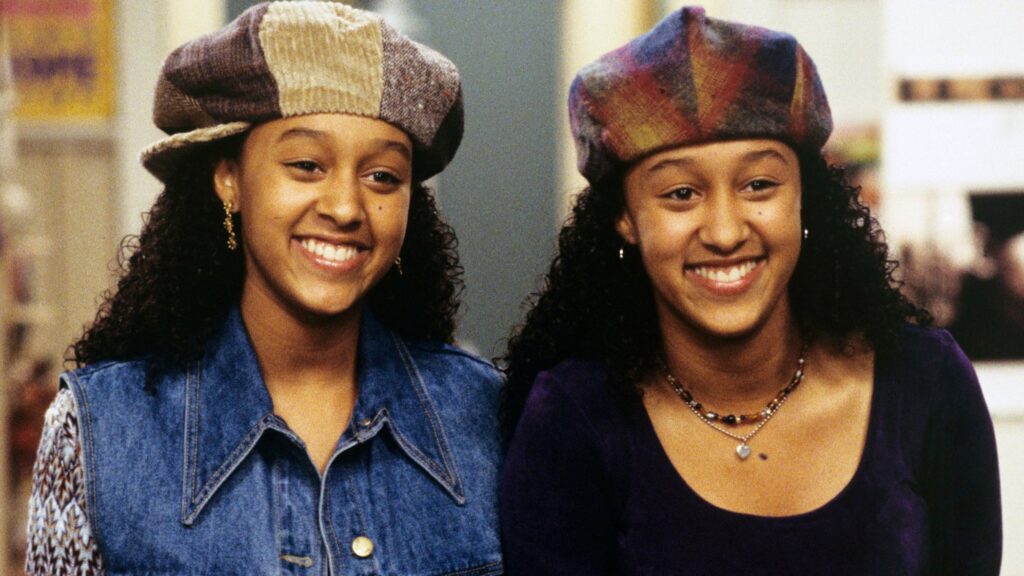 10 Insanely Popular TV Shows From the ‘90s You Can Stream on Netflix 38 Scene from "Sister, Sister" featuring the twins, Tia and Tamera, wearing matching colorful berets and smiling at the camera.
