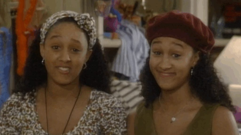 10 Insanely Popular TV Shows From the ‘90s You Can Stream on Netflix 40 Scene from "Sister, Sister" featuring the twins, Tia and Tamera, wearing matching headwraps, both smiling.