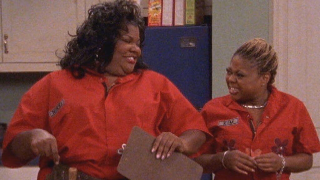 10 Insanely Popular TV Shows From the ‘90s You Can Stream on Netflix 49 Scene from "The Parkers" showing Nikki and Kim in matching orange uniforms standing together and laughing.