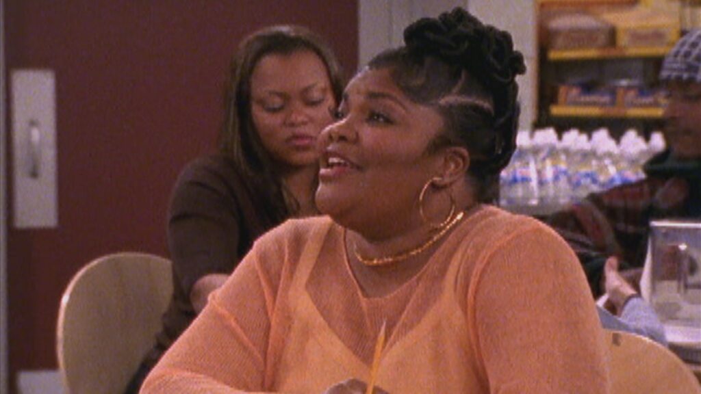 10 Insanely Popular TV Shows From the ‘90s You Can Stream on Netflix 48 Scene from "The Parkers" featuring Nikki in an orange/peach colored top sitting at a table, with another person visible in the background.