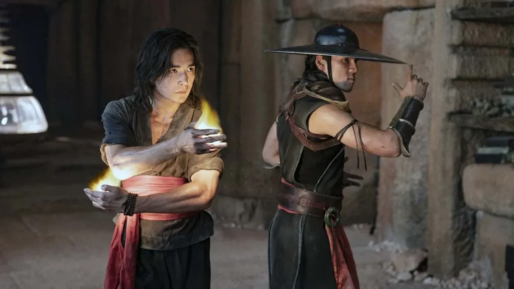 Mortal Kombat 2: Everything We Know So Far 2 Liu Kang and Kung Lao from the Mortal Kombat movie in fighting stances, with Liu Kang channeling fire energy and Kung Lao wielding his signature razor-rimmed hat.