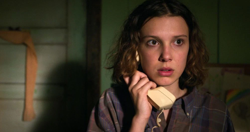 How Old Is ‘Stranger Things’ Cast: Actors’ Age in Season 1 and Season 5 1 Eleven is holding a telephone receiver to her ear, looking intently to the side.