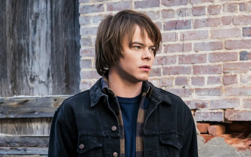 How Old Is ‘Stranger Things’ Cast: Actors’ Age in Season 1 and Season 5 8 Jonathan Byers is wearing a dark denim jacket over a blue shirt. He is looking to his right.