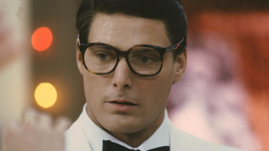 Clark Kent looks thoughtfully to the side, wearing a white tuxedo and bow tie.