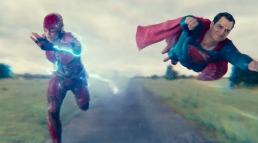 The Flash is running on a road, while Superman is flying alongside him.