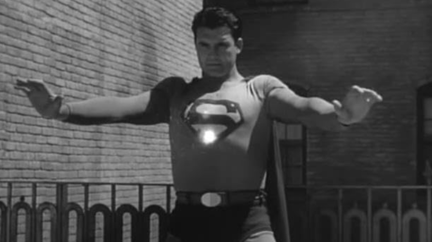 Superman stands with his arms outstretched, facing forward.