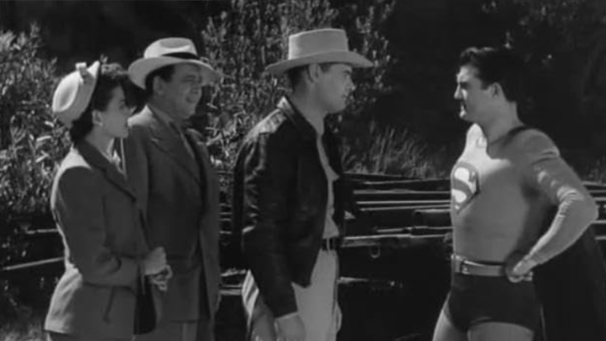Superman is talking to a group of three people.