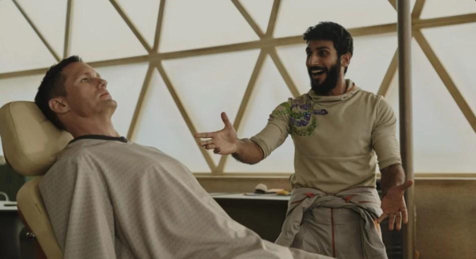 Alexander Skarsgård and Akshay Khanna share a lighthearted moment in a scene from Murderbot.