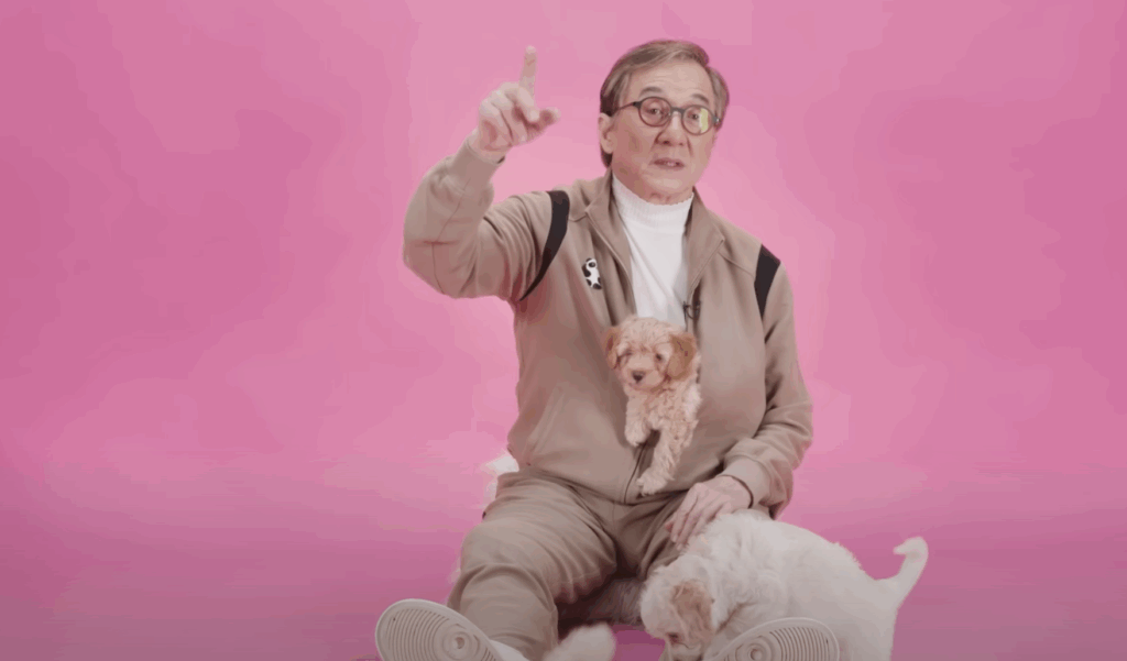 Jackie Chan Made $256M but Still Dragged One of His Best Films Like It Was a Big Mistake 1 Jackie Chan, sitting on the floor, playing with puppies.