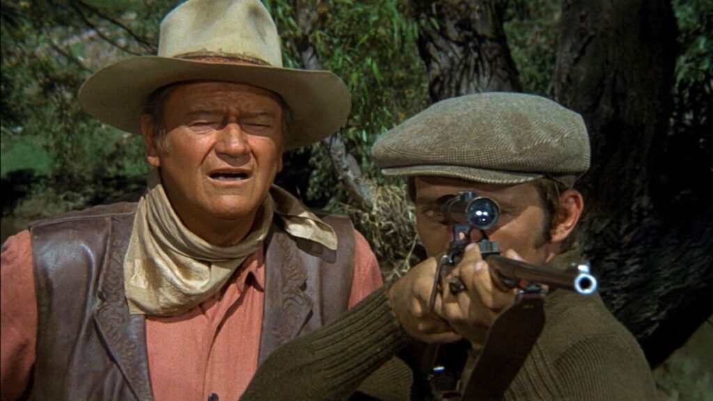 Quentin Tarantino Declares His Favorite 1950 Western Director, and It’s Not Philip Ford 1 A shooter looking through a gun's scope and a sighter looking over him with squinted eyes in a still from Big Jake.