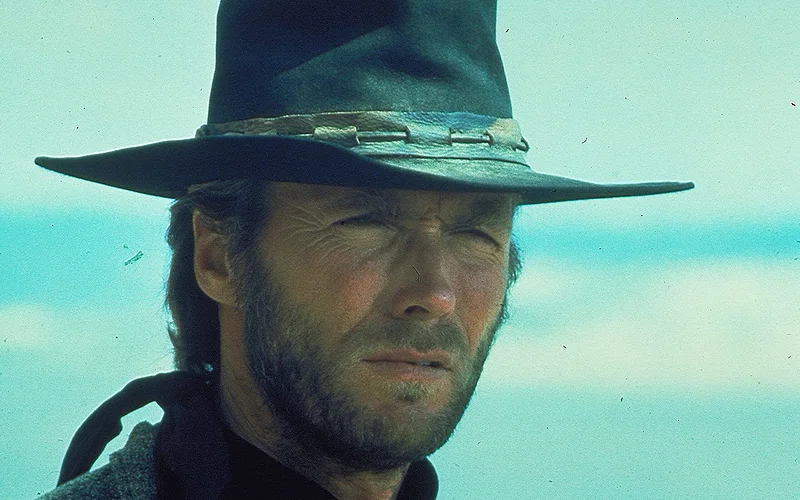 Clint Eastwood squinting while wearing a cowboy hat.