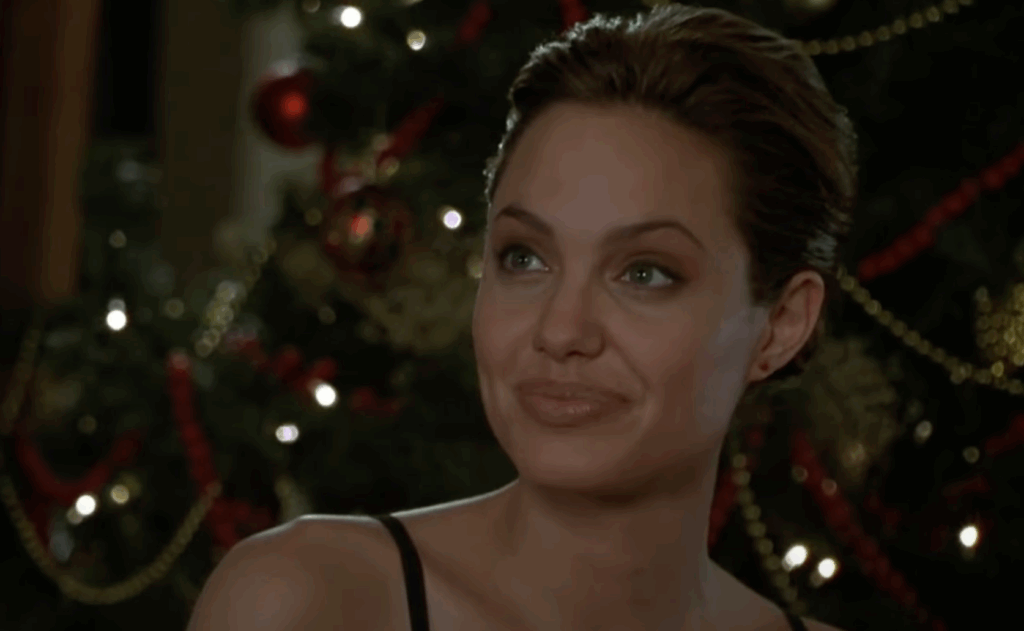 Angelina Jolie in a black dress and hair bun. 