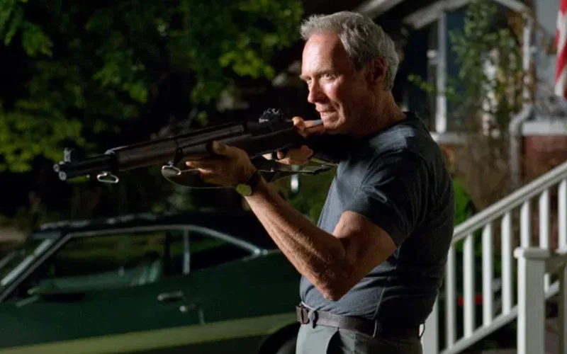 Clint Eastwood holding a gun outside of his house