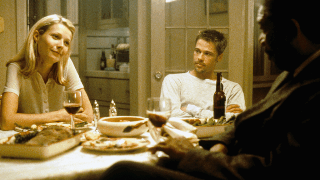 Gwyneth Paltrow and Brad Pitt sitting at a table in the film, Se7en.