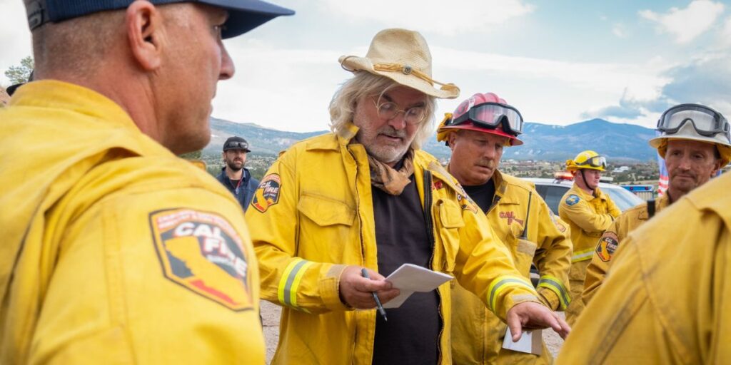 'The Lost Bus' on Apple TV+: Release Date, Cast, Plot, and All You Need to Know 5 Paul Greengrass directing The Lost Bus film in a yellow jacket and white hat
