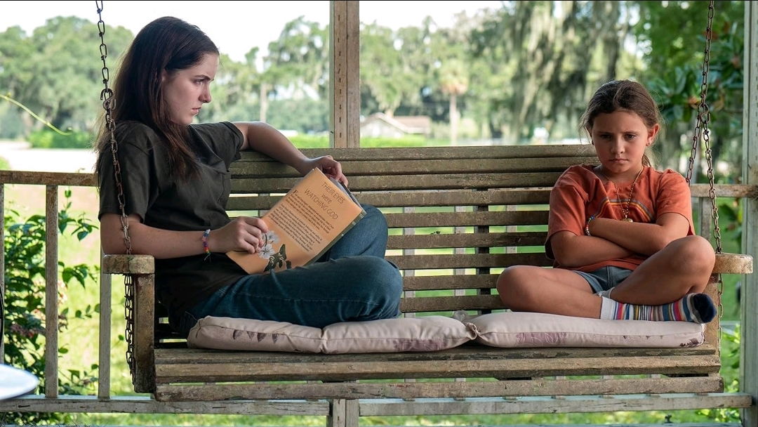 What We Hide Review — Mckenna Grace Anchors a Haunting and Profound Tale of Survival 4 Two girls sit on a porch swing