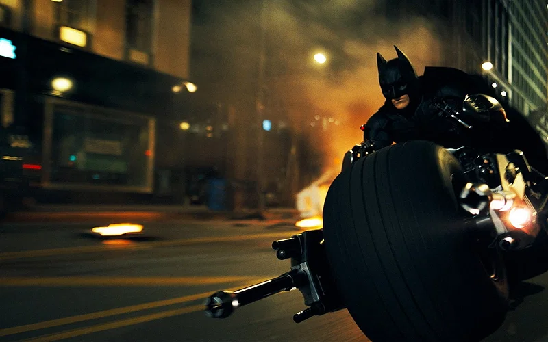 Christian Bale riding the Batpod as Batman in a still from The Dark Knight from 2008