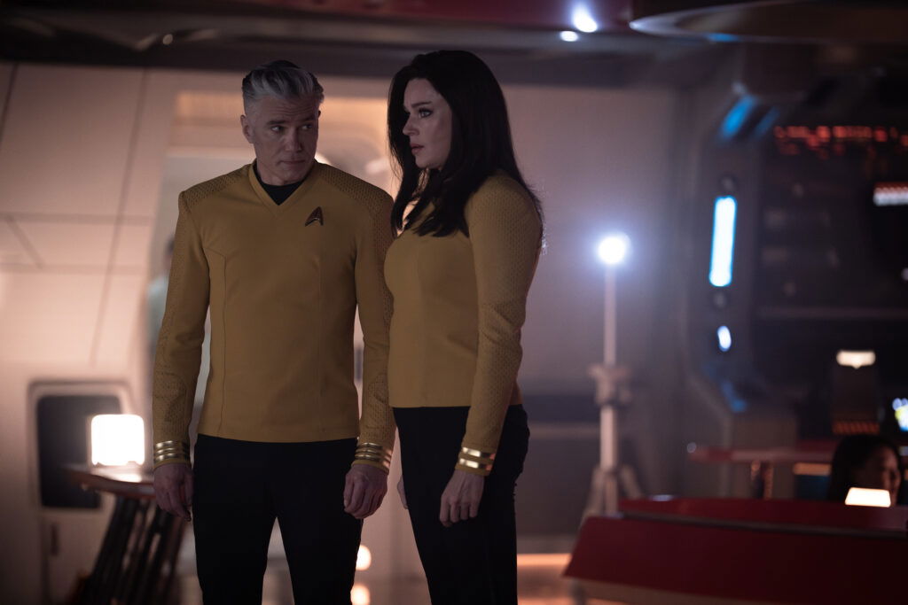 A still from Star Trek: Strange New Worlds Season 3 featuring Pike and Una standing in a room
