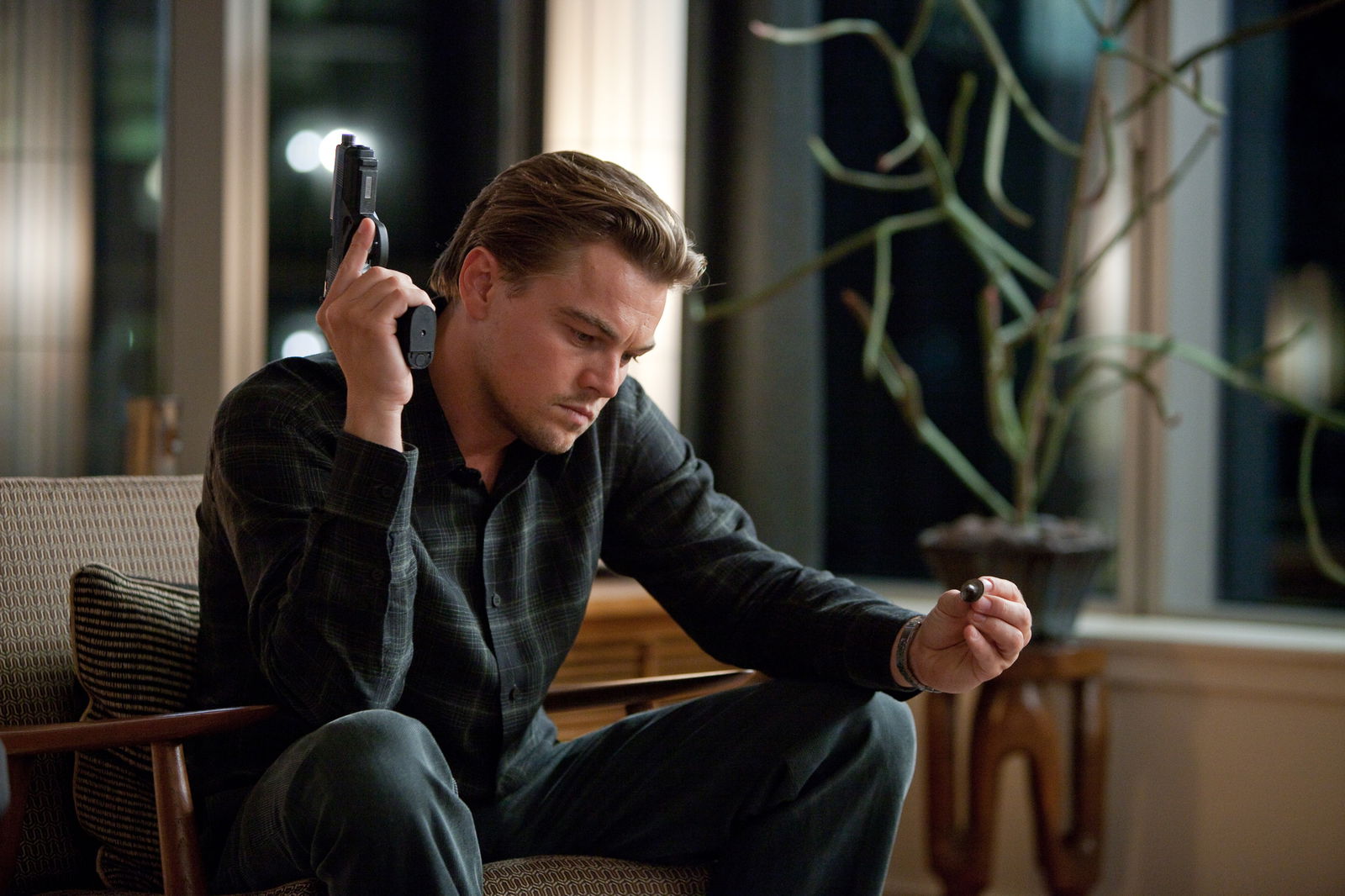 Leonardo DiCaprio holding a gun in a still from Inception 