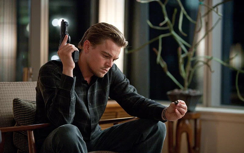 Leonardo DiCaprio holding a gun in a still from Inception