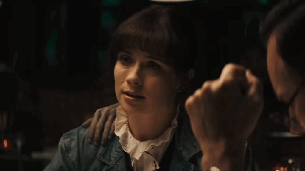 A woman sitting with a demon’s hand on her shoulder from The Conjuring: Last Rites