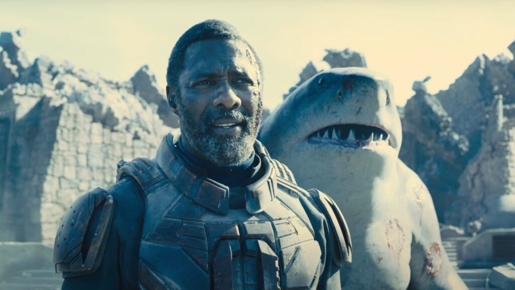 Idris Elba as Bloodsport standing next to shark in The Suicide Squad