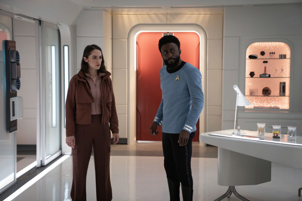 A still from Star Trek: Strange New Worlds Season 3 featuring Batel and M'Benga standing in the medical bay