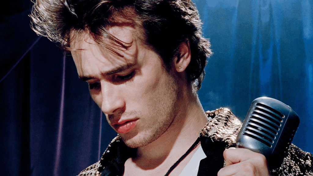 Jeff Buckley holding his mic and looking down while singing. 