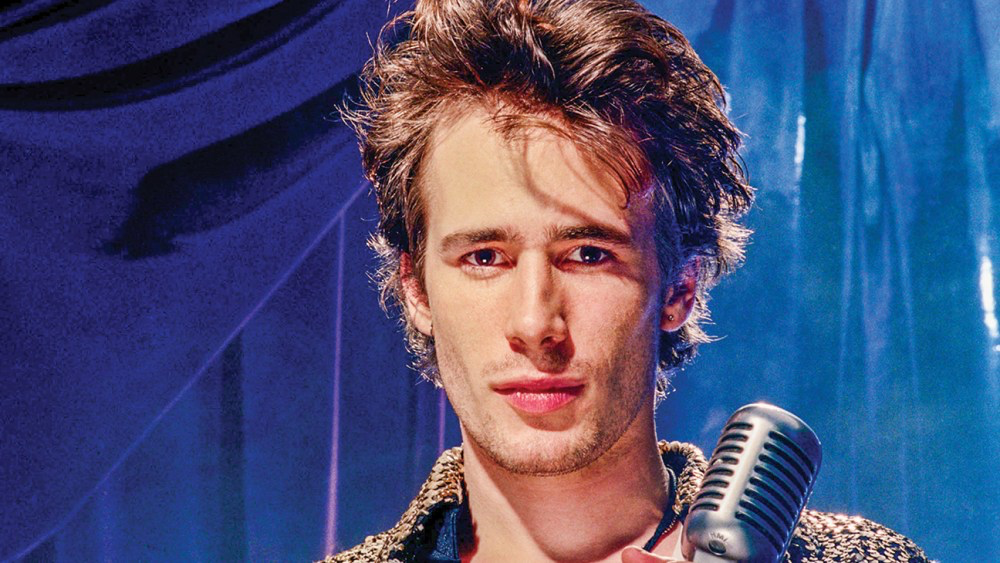 Jeff Buckley looking at the camera while holding the mic in an archive footage from It’s Never Over, Jeff Buckley.