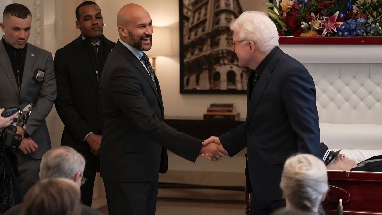 A man shakes the hand of a podcaster at a funeral