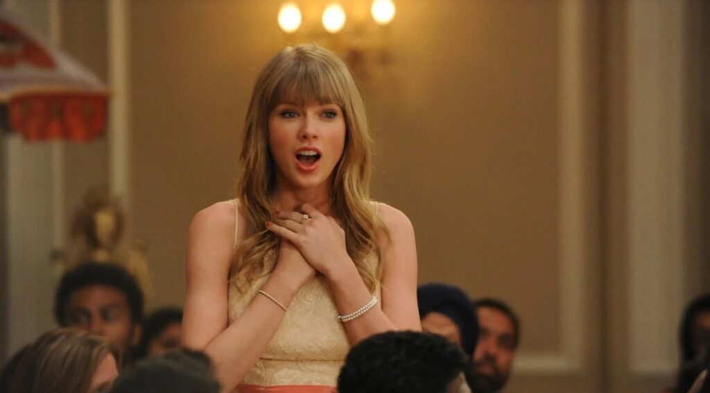 Taylor Swift clasping her hands in scene from New Girl