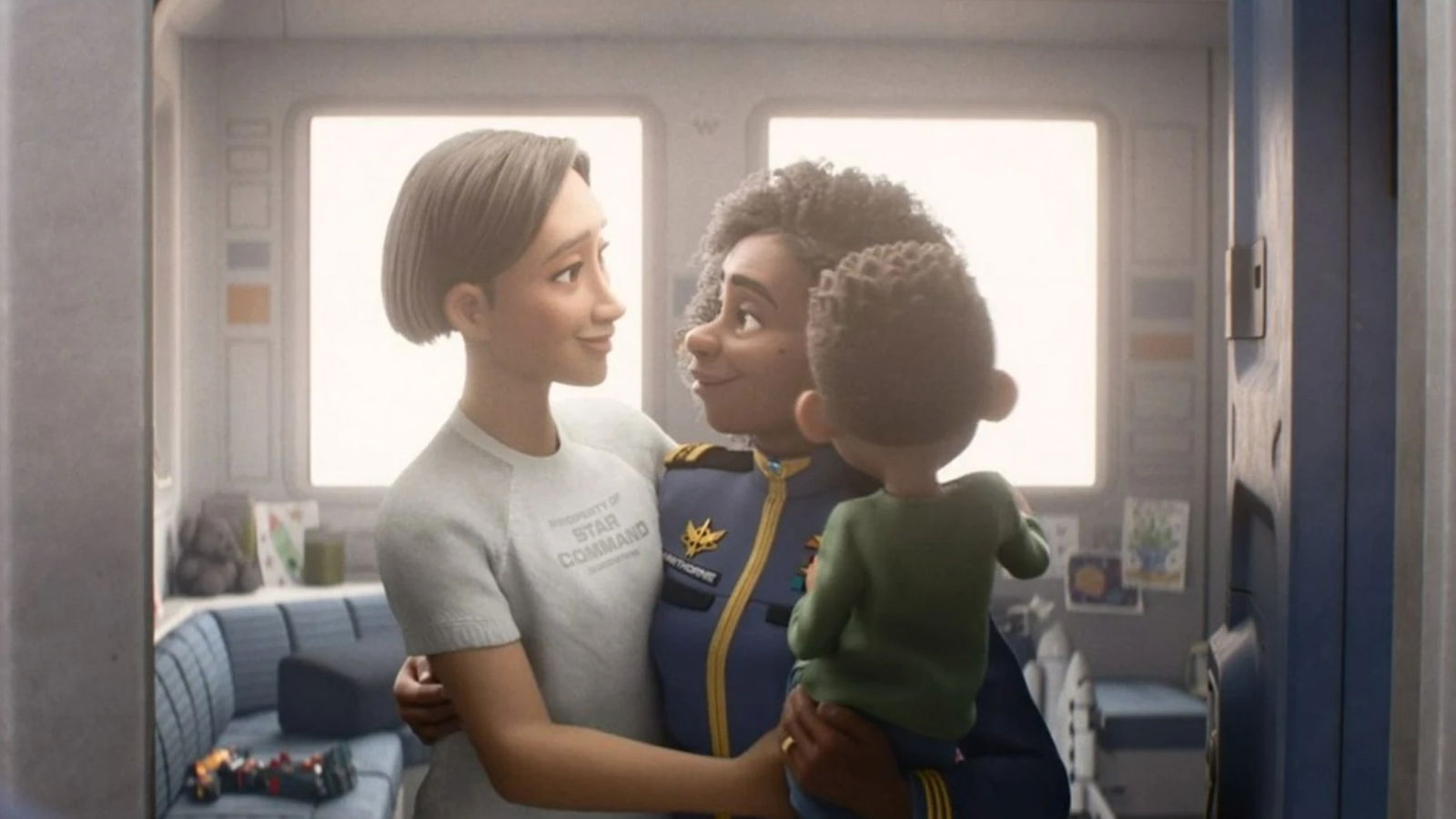 Kiko in a gray "Star Command" shirt embraces a Alisha Hawthorne in a blue military-style uniform who is holding a small child.