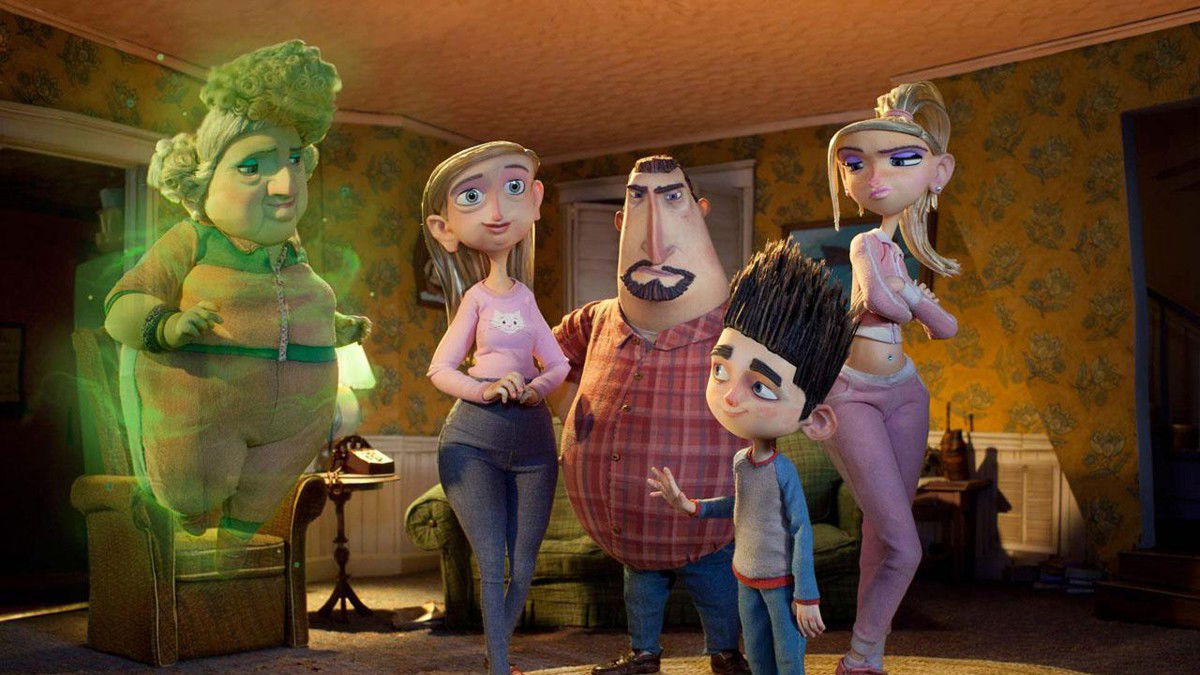 A family group stands together in a living room. Grandma Babcock glowing with green light, Sandra, Perry in a plaid shirt, Norman, and Courtney in casual clothes.