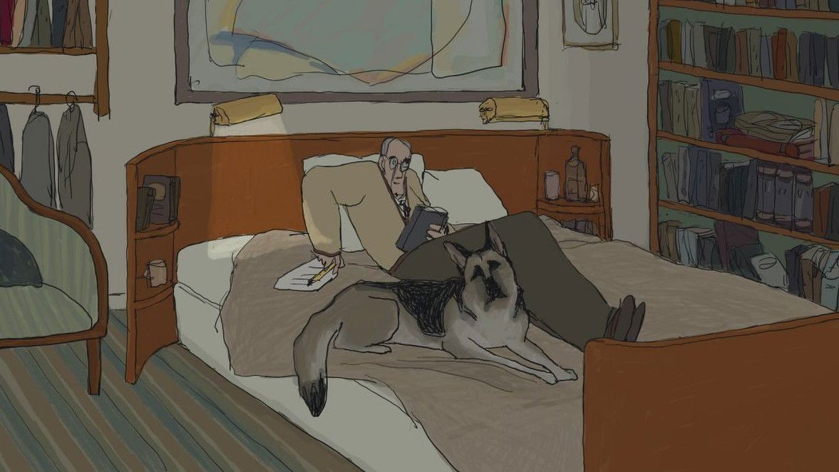 Ackerley lying in bed reading, with Tulip resting on the bed beside him, in a cozy bedroom setting filled with bookshelves.