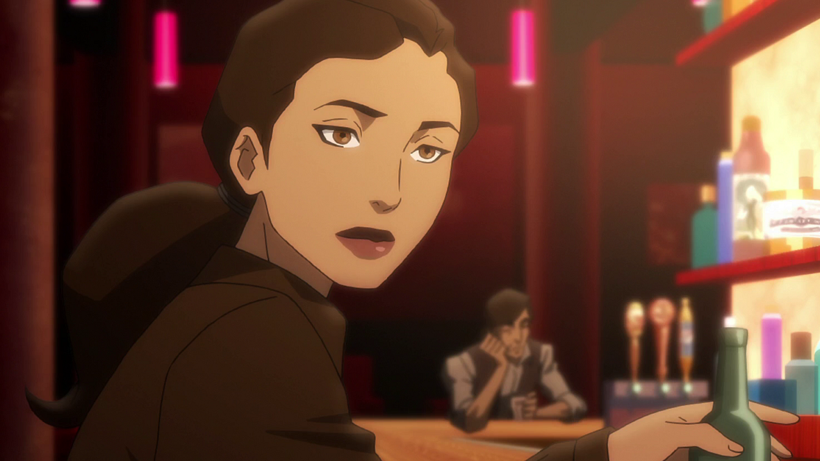 Renee Montoya with shoulder-length dark hair in casual clothing, sitting in a dimly lit bar.