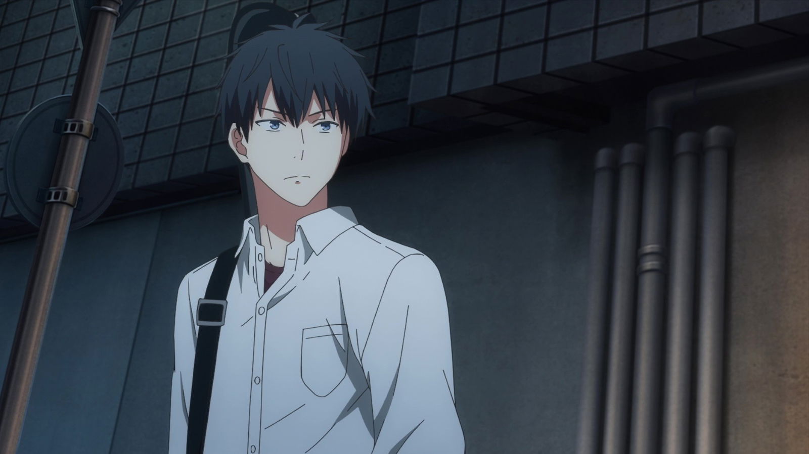 Ritsuka Uenoyama with dark hair in a white shirt standing outdoors against a building backdrop, appearing serious or contemplative.
