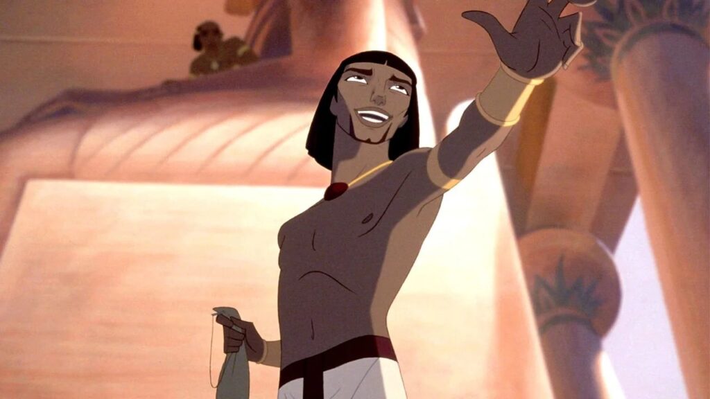 15 Animated Movies That Celebrate LGBTQ+ Characters 1 Moses from “The Prince of Egypt” with dark hair celebrating with arms raised triumphantly against a warm orange and pink sunset backdrop, appearing joyful and victorious.