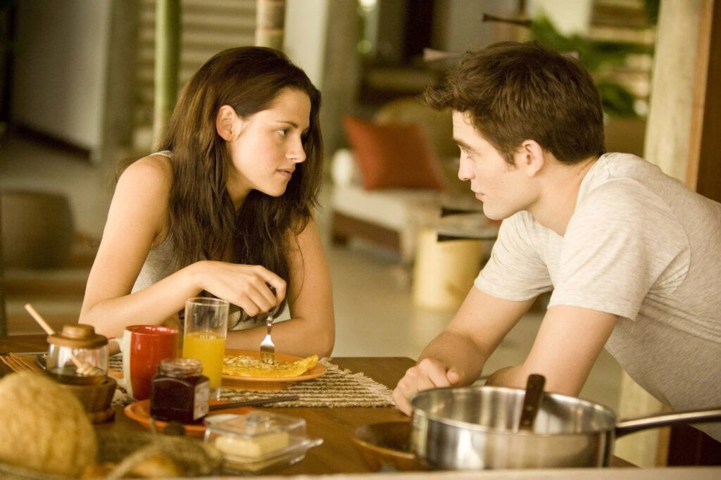 Bella and Edward are staring at each other while having breakfast