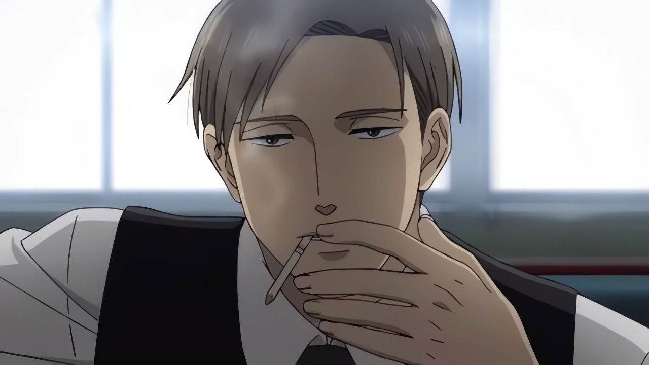 Yashiro with light hair in a business suit sitting thoughtfully with his hand near his face, smoking, photographed in an office setting.