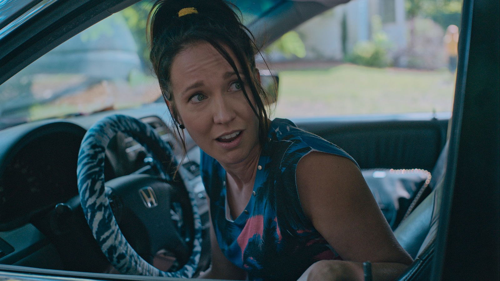 A woman looks back while inside her car