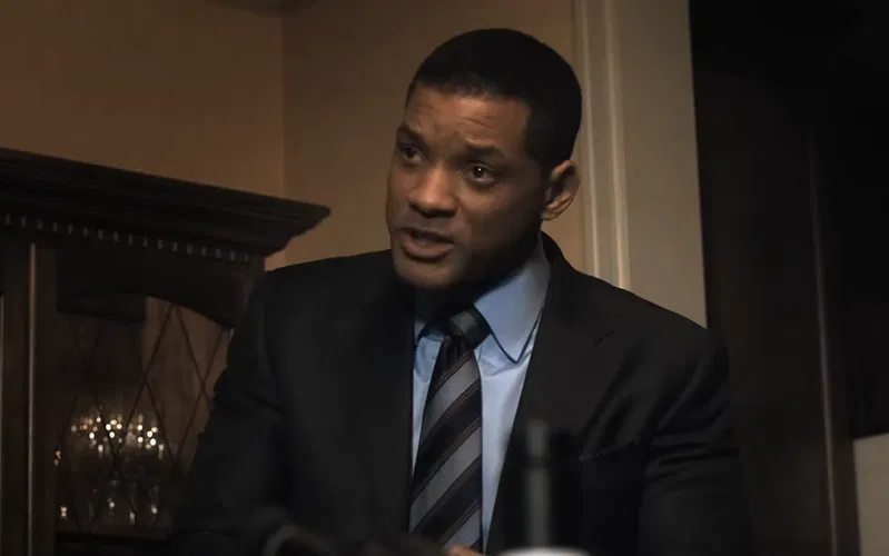 Will Smith wearing a black blazer, blue shirt, and a striped tie.