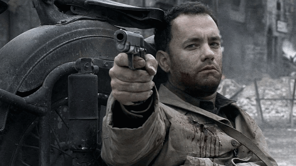 Tom Hanks as Captain Miller pointing his gun towards someone looking dejected and wounded in Saving Private Ryan