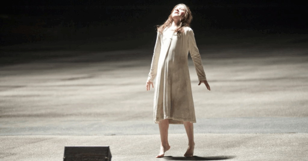 A kid talking on her toes on the streets with a white dress on. 