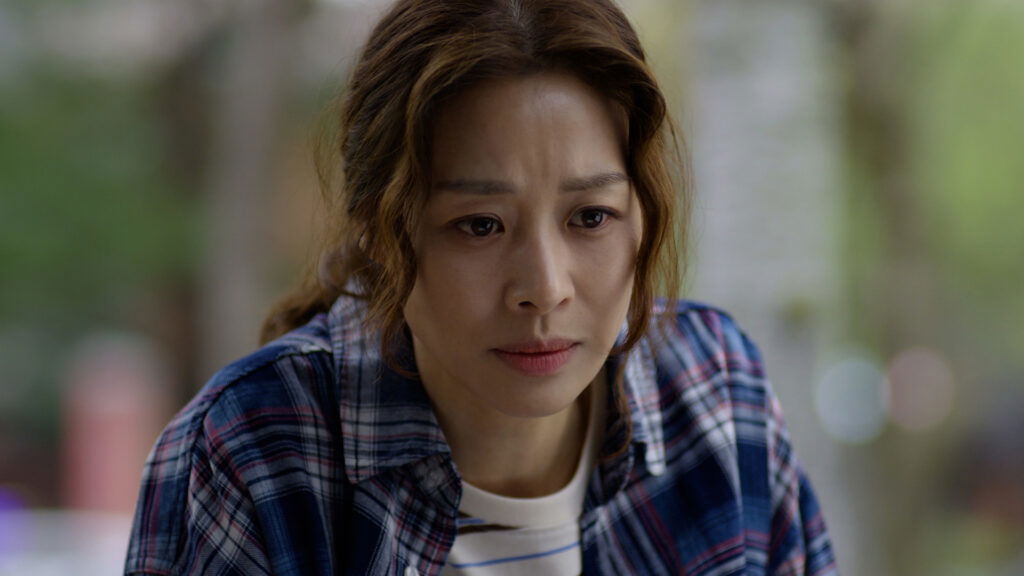 Jang Shin-young in The Woman Who Swallowed the Sun wearing a ble checkered shirt over a white tee.