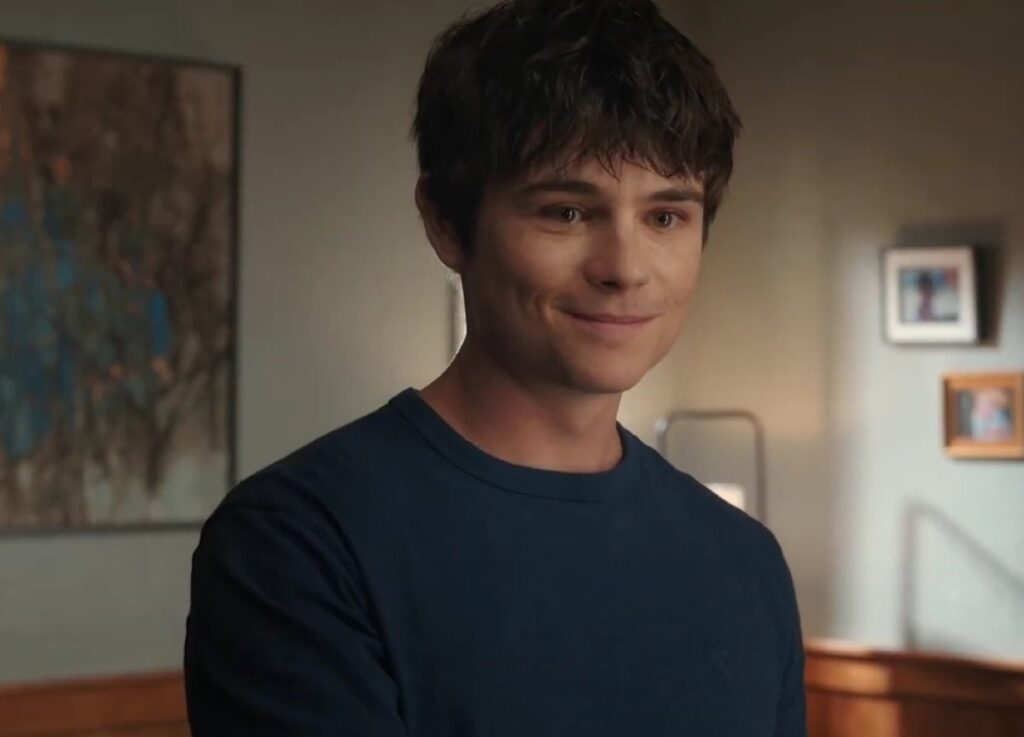 A man with black hair in a navy blue hoodie
