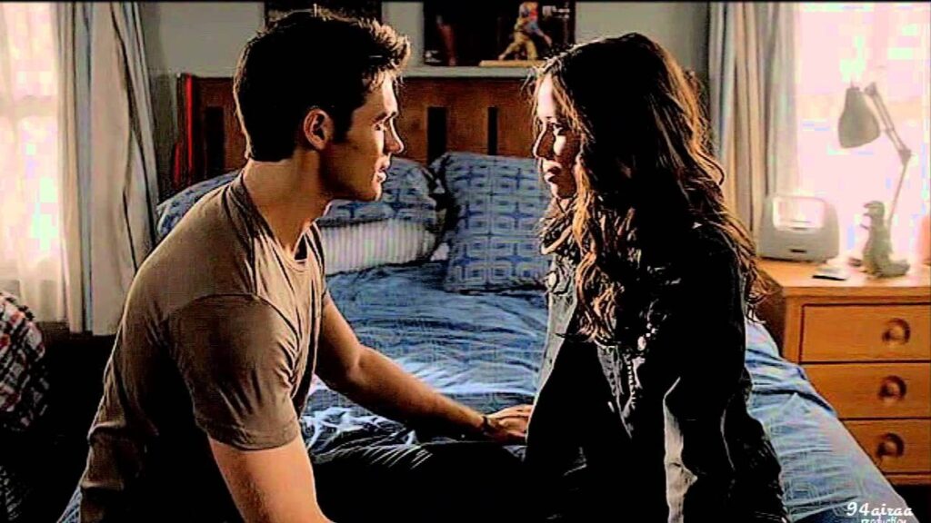 Jeremy and Anna sitting together on a bed in Jeremy's bedroom, having an intimate conversation.