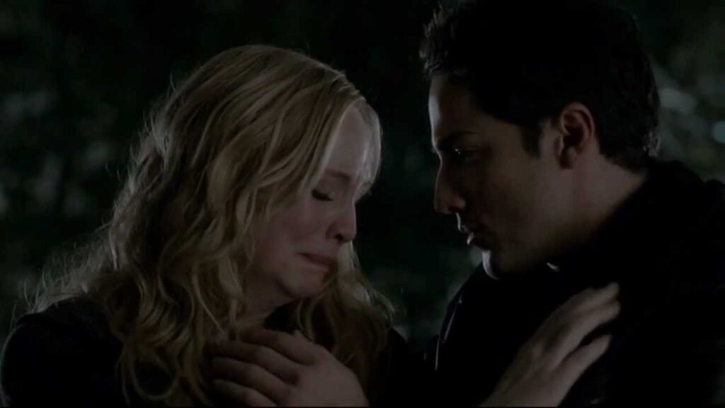 Caroline and Tyler in an outdoor night scene with natural lighting. Caroline is crying and Tyler is comforting her.