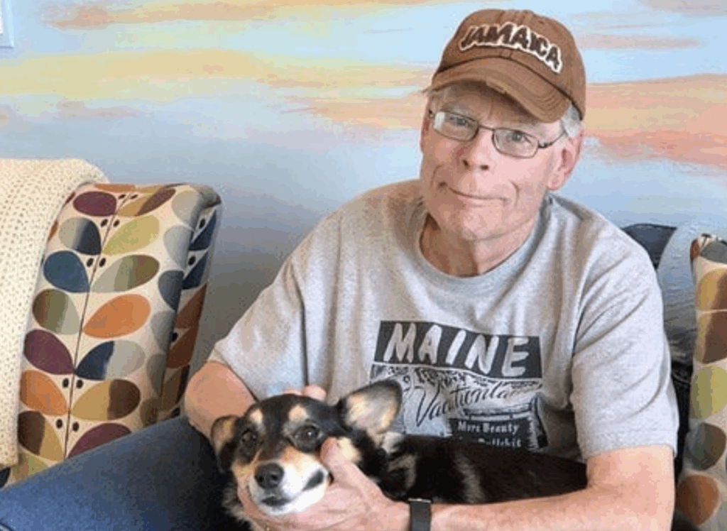Stephen King posing with his dog for a picture.
